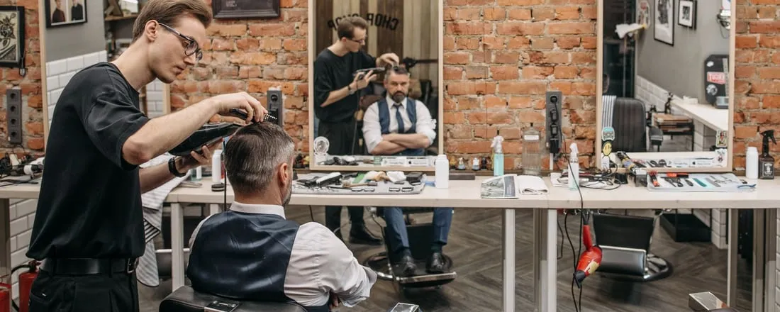 Barber strzyże klienta w zakładzie fryzjerskim